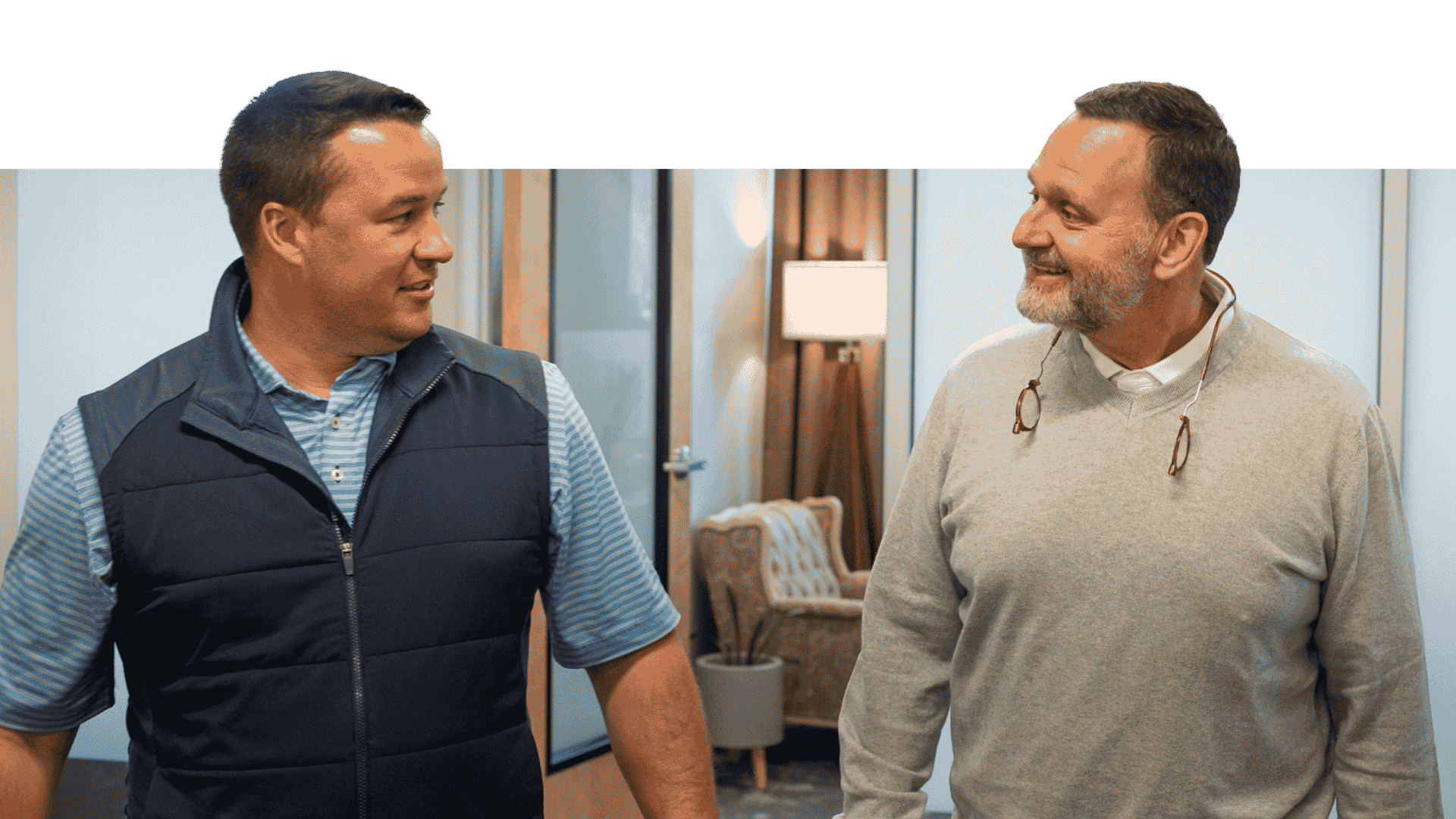 2 males walking and talking in an office hallway